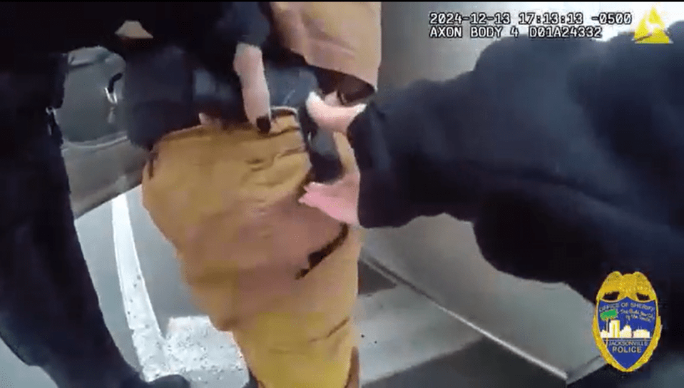 Police officer removing a gun from a suspect's waistband.