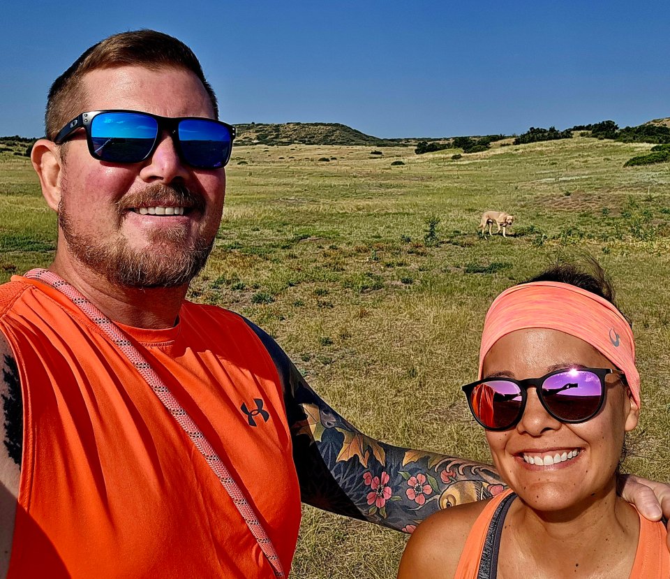 A man and woman outdoors, smiling for a selfie.