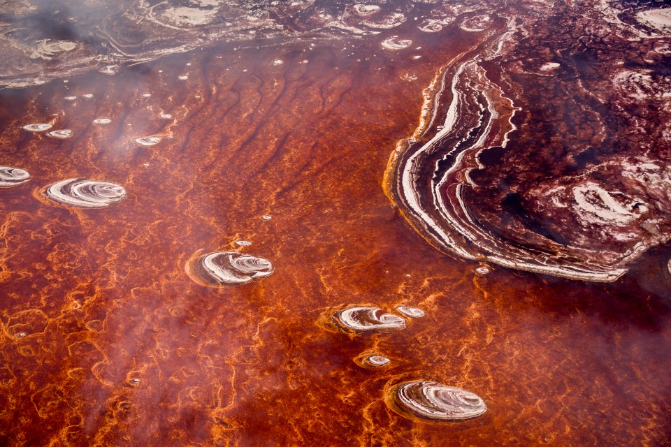 Aerial view of Lake Natron in Tanzania, showing patterns of red algae and salt formations.