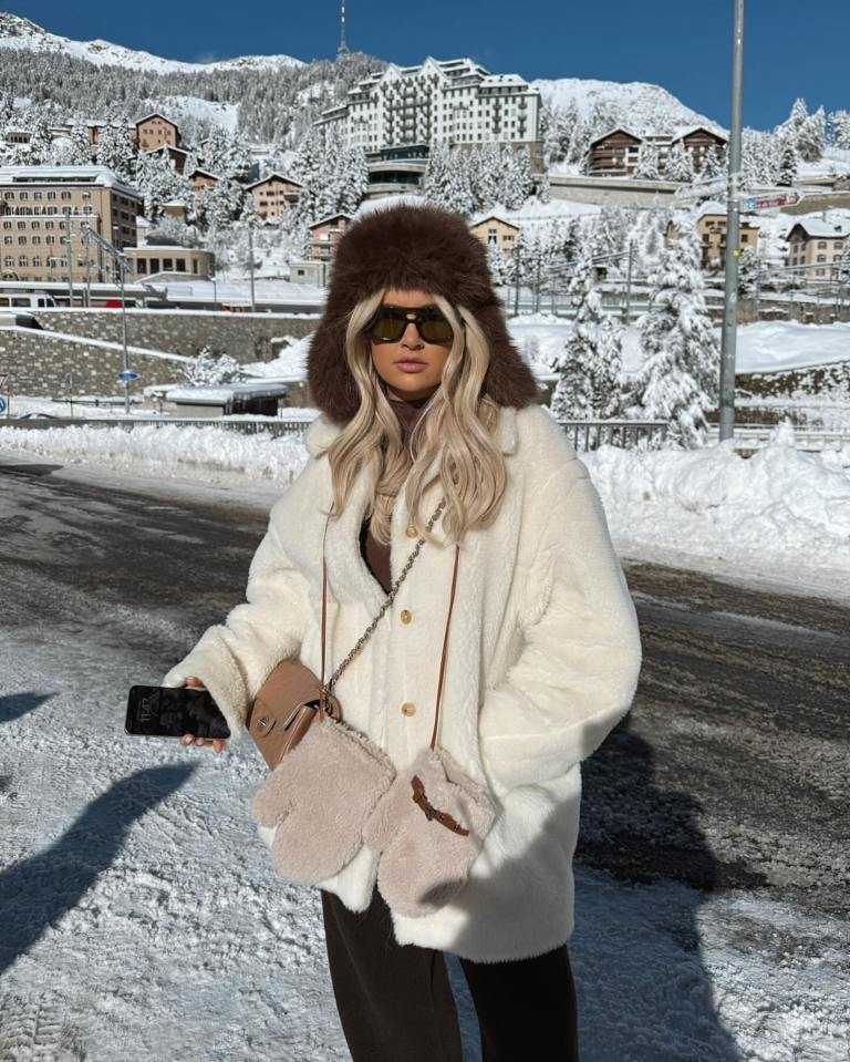 Woman in white fur coat and brown fur hat in snowy St. Moritz.