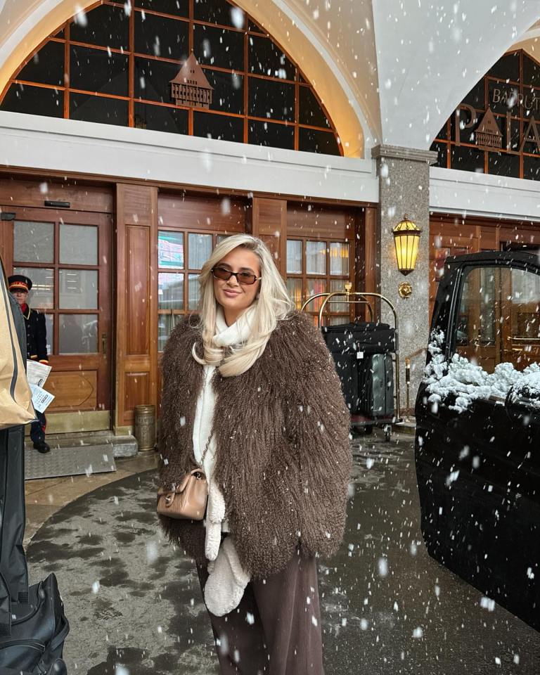 Woman in brown coat outside in the snow.