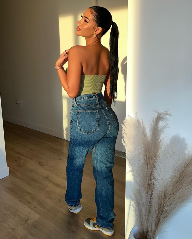 Woman in olive green crop top and blue jeans.