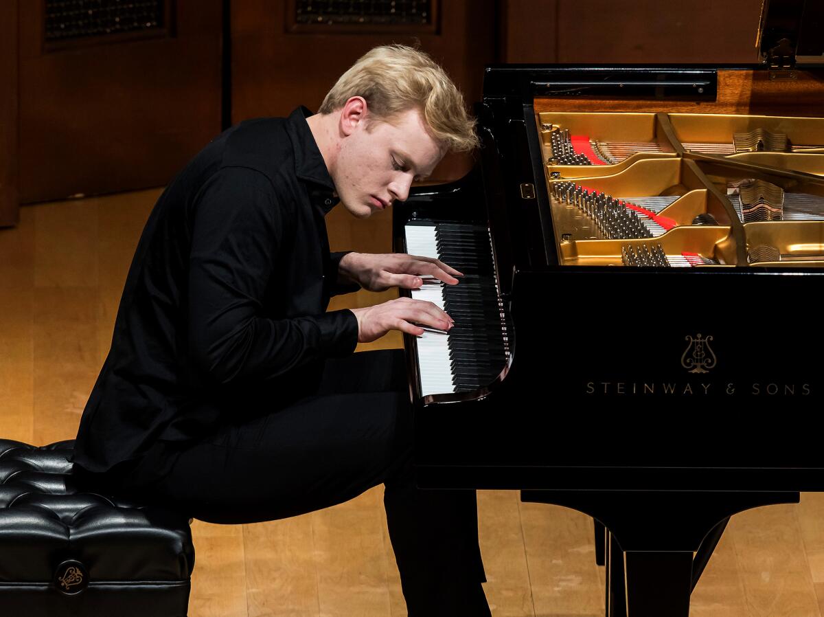 A concert pianist leans over the keyboard, his eyes closed and head tilted