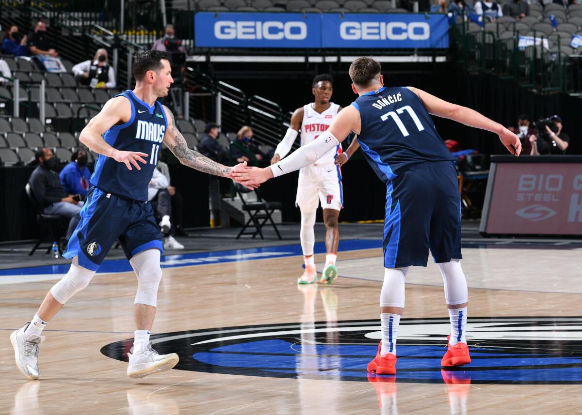 Mavericks teammates JJ Redick, left, and Luka Doncic, right, slap hands during a game on April 21, 2021, in Dallas.