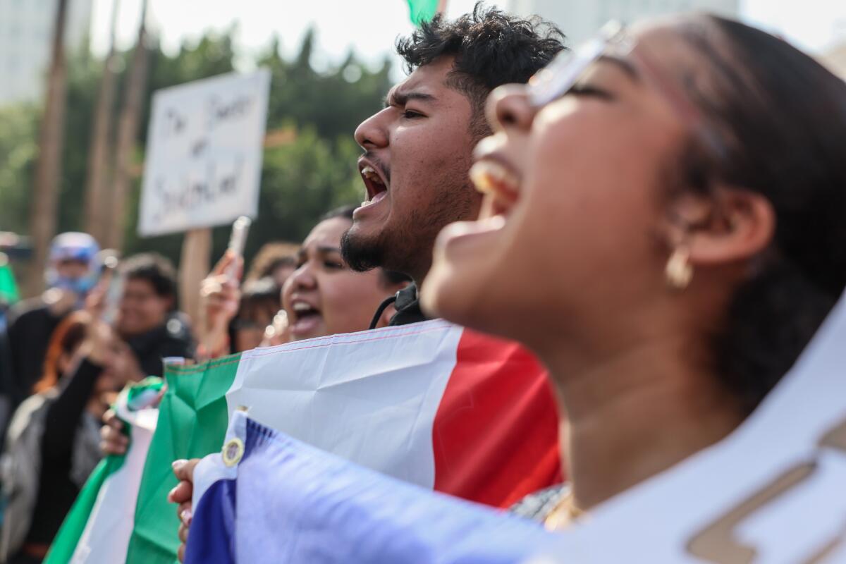 People, some holding green, white and red flags, shout during a protest 