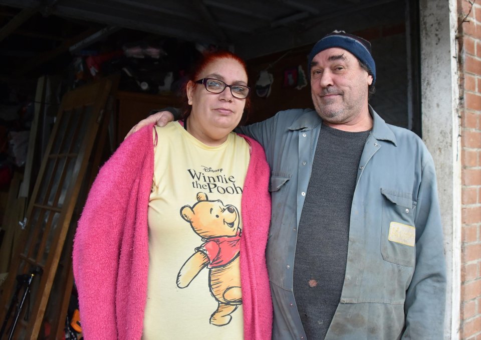 Portrait of a couple standing in a cluttered garage.