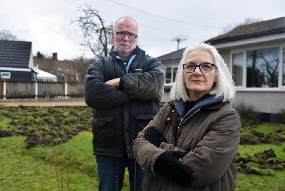 Couple standing in their garden, which has been damaged by pigs.