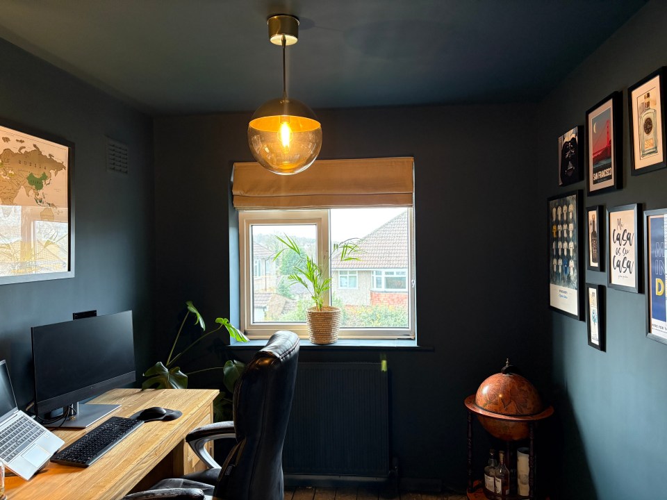 Home office with dark walls, wood desk, and globe.