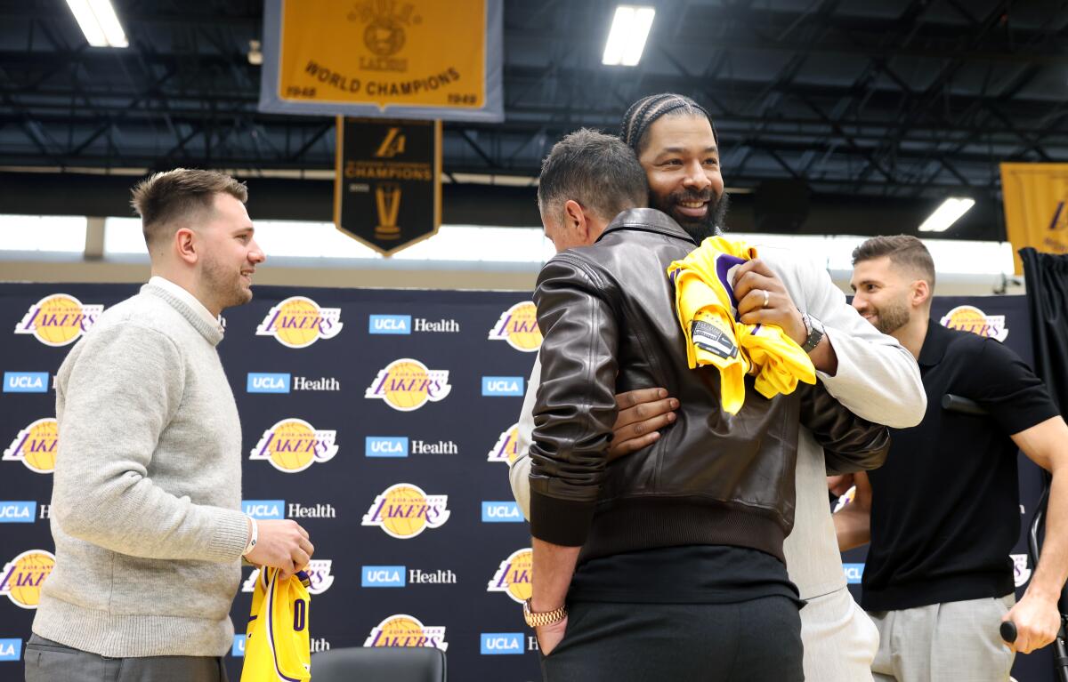 Lakers general manager Rob Pelinka, center, and forward Markeiff Morris embrace.