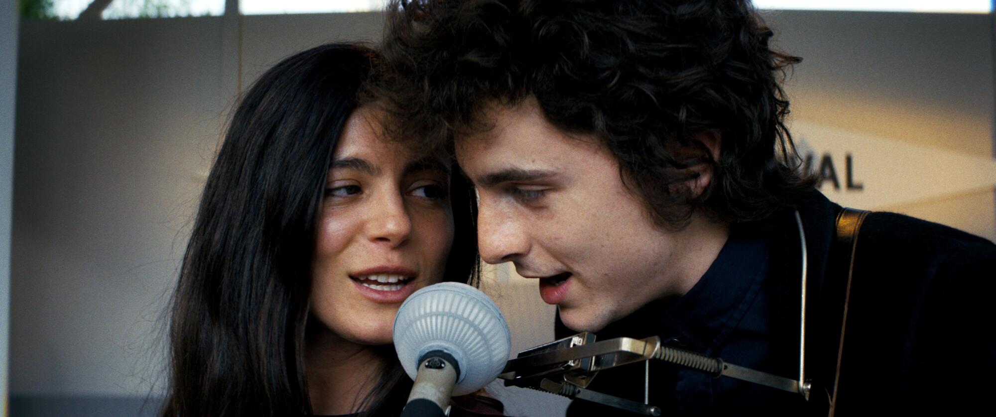 A man and woman lean in close to sing at the same microphone in "A Complete Unknown."