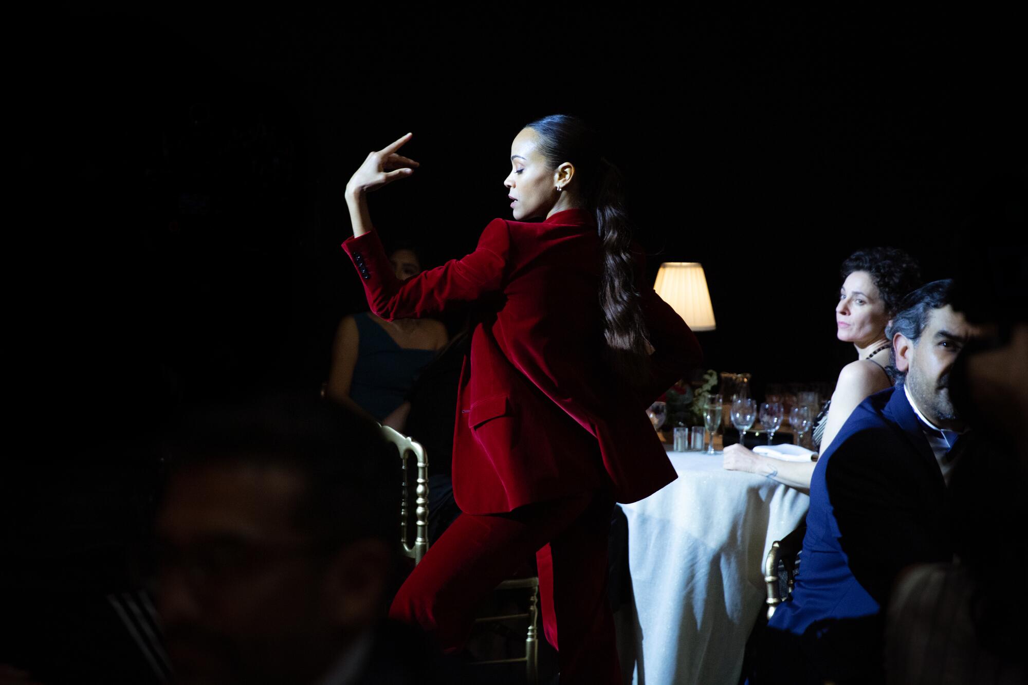 A woman in a spotlight dances as diners look on in "Emilia Pérez."