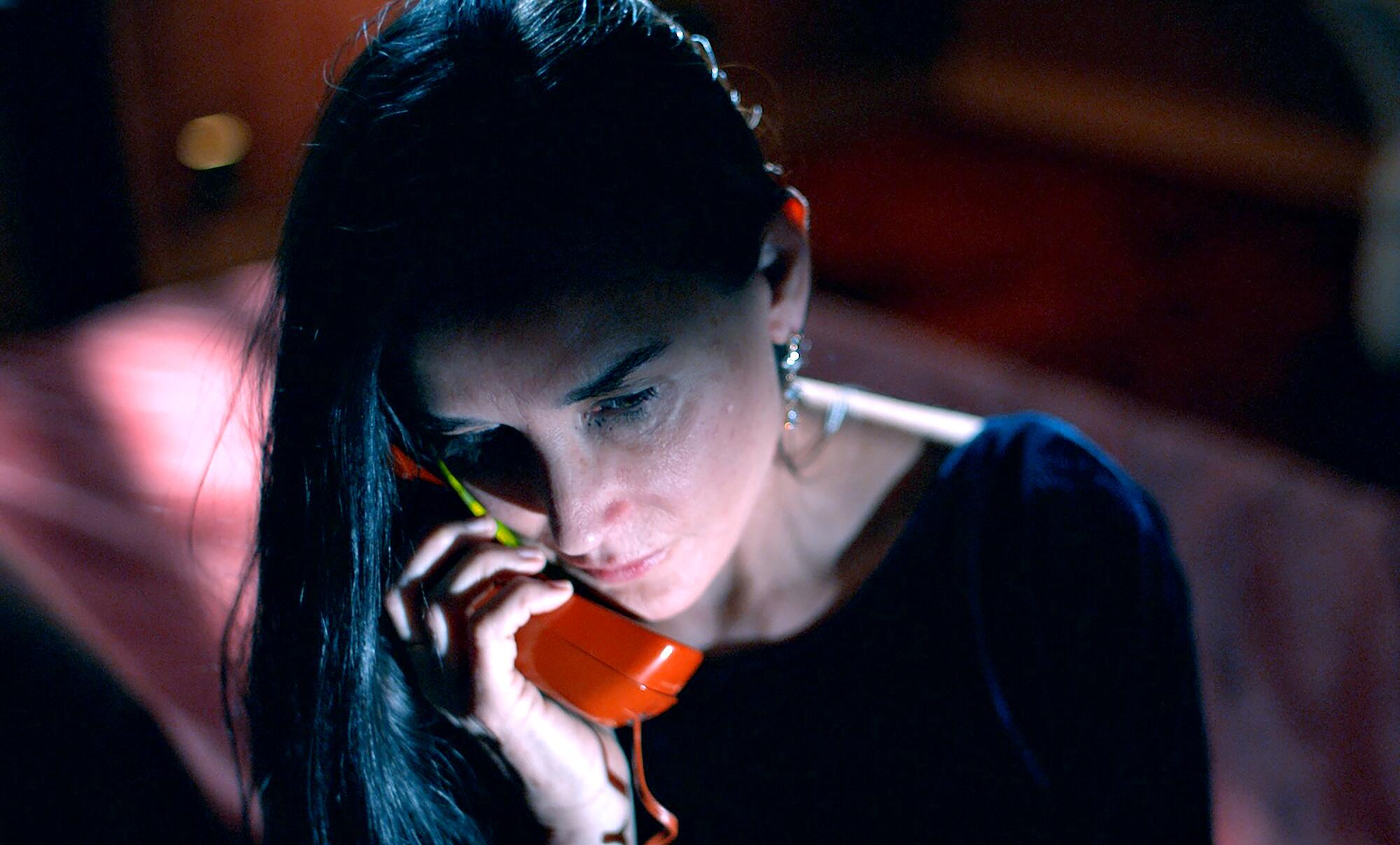 A woman in shadows talks on the phone in "The Substance."