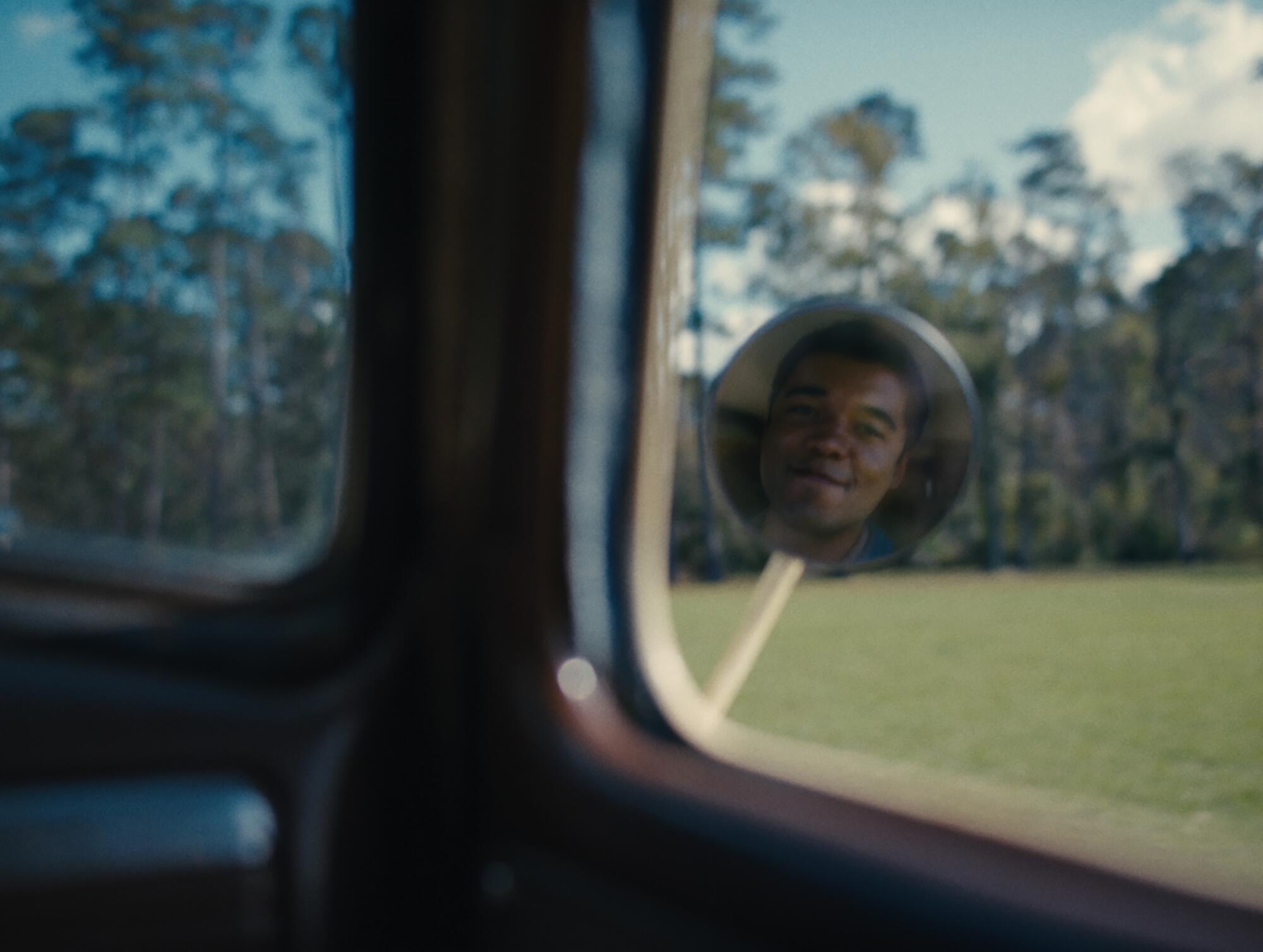 A man's face is reflected in the side mirror of a car in "Nickel Boys."