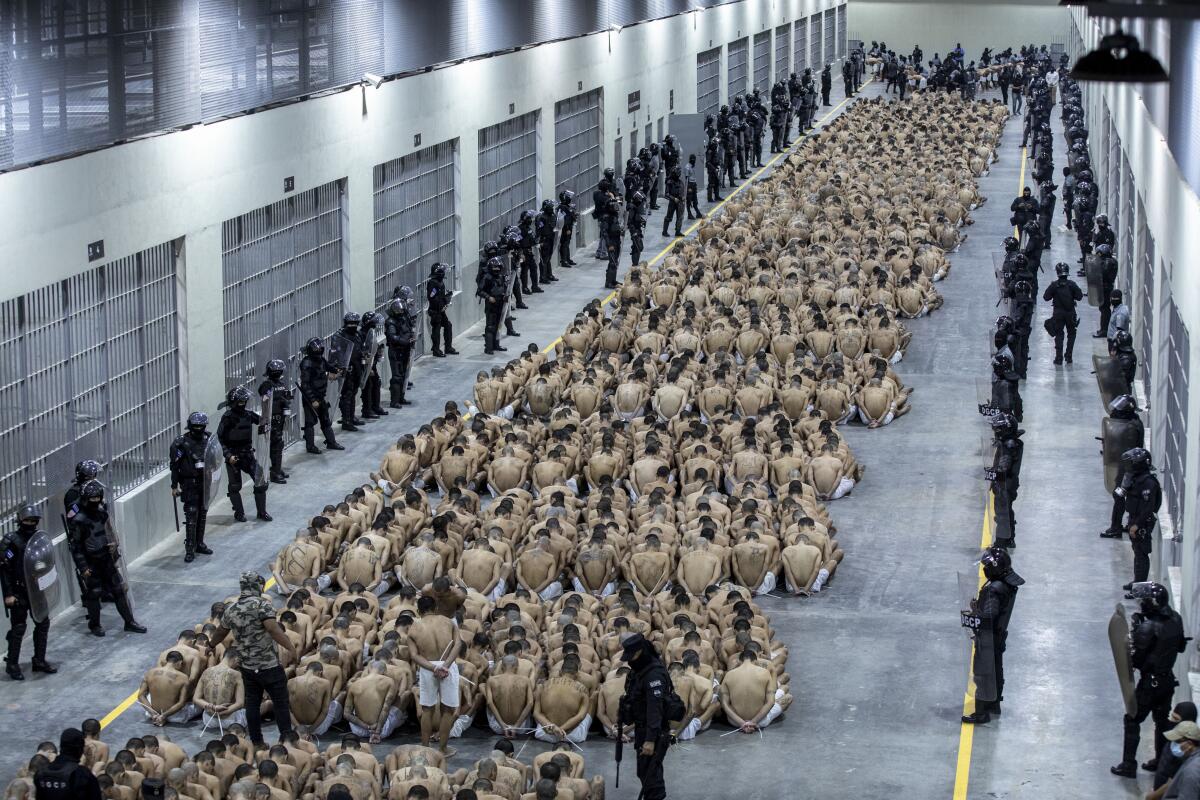 Inmates seated in groups on the floor of a prison