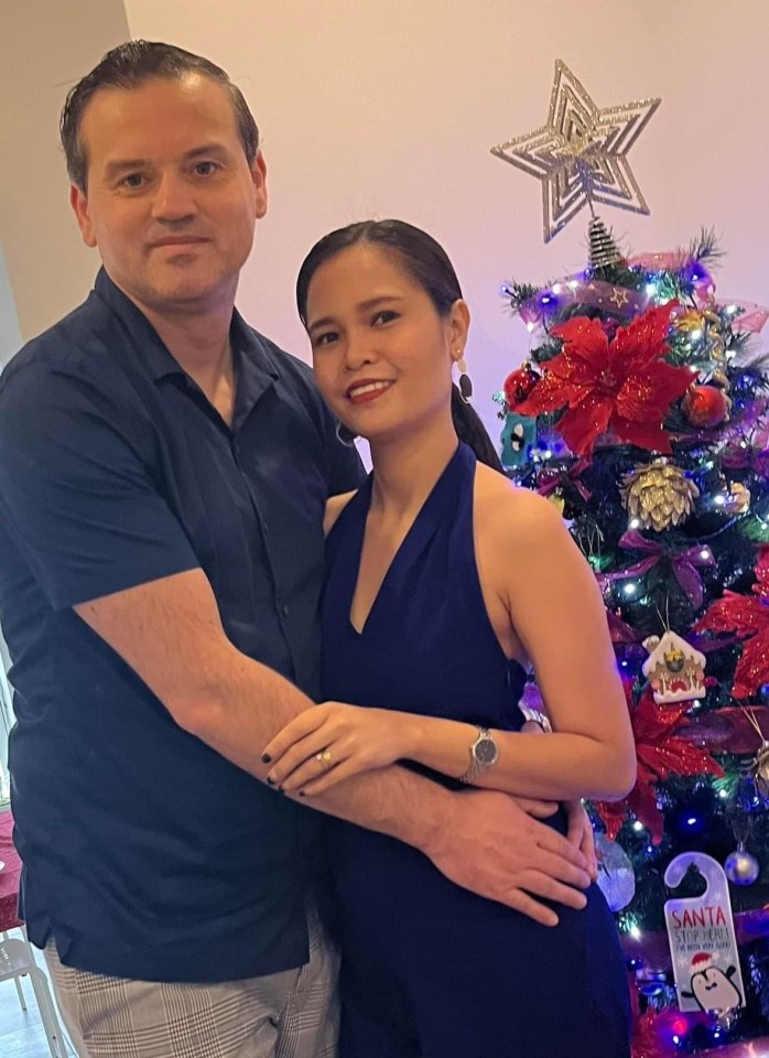 Couple posing by a decorated Christmas tree.