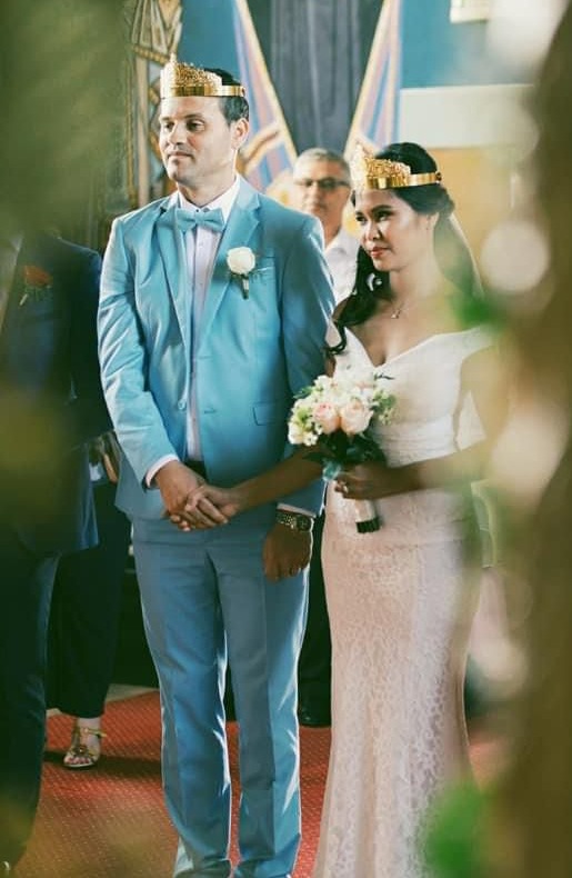 Bride and groom in a church, wearing crowns.