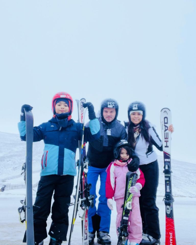 Family of four in ski gear posing with skis.