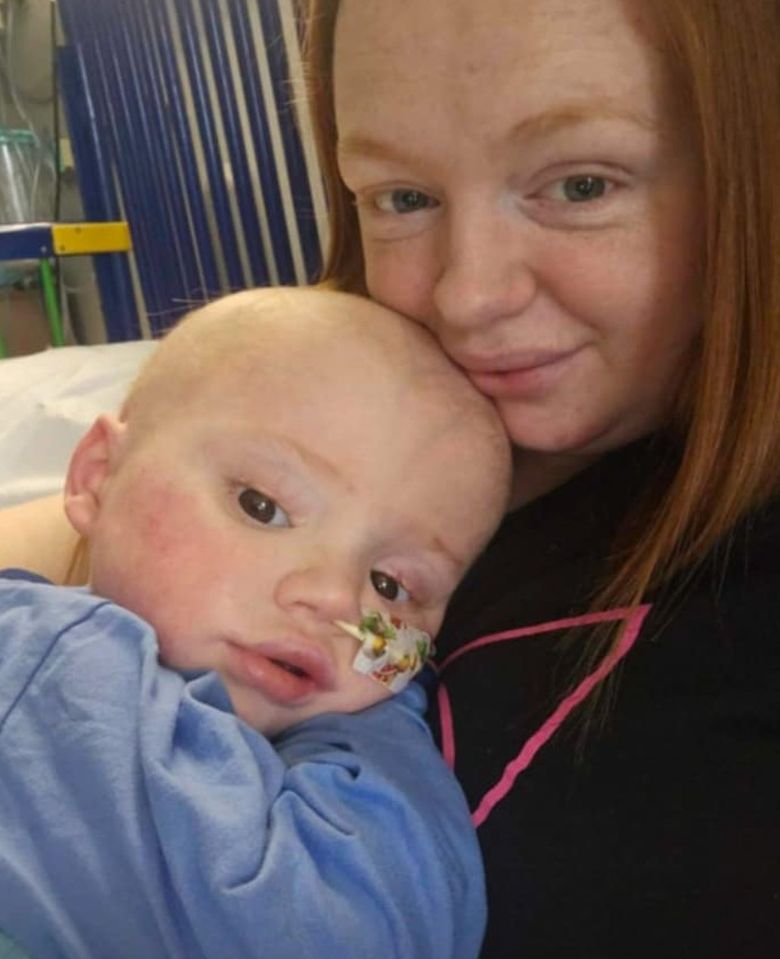 A mother holding her young son who is ill in a hospital bed.