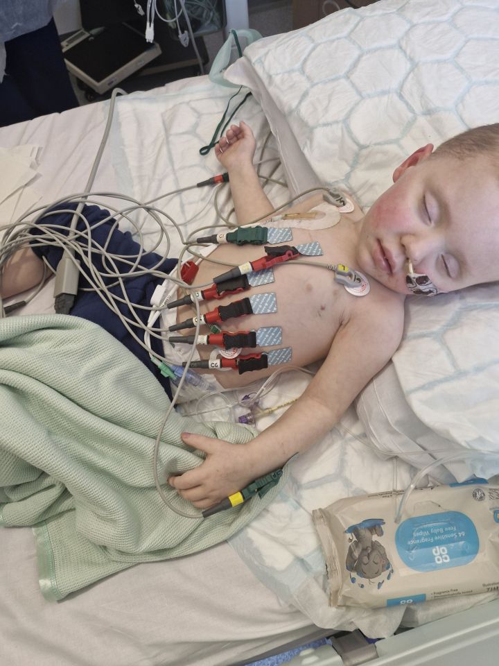 A young boy with stage-four cancer connected to medical equipment in a hospital bed.