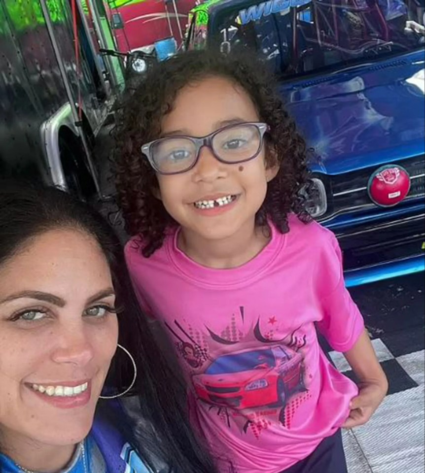 A woman and a girl in front of a race car.