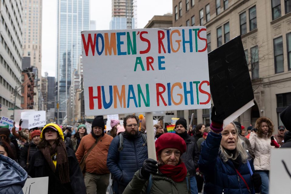 A protester holds a sign that reads "WOMEN'S RIGHTS ARE HUMAN RIGHTS" at a demonstration.