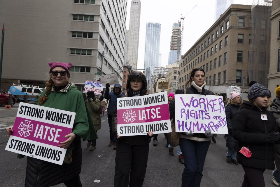 Protesters march holding signs advocating for worker rights and strong unions.