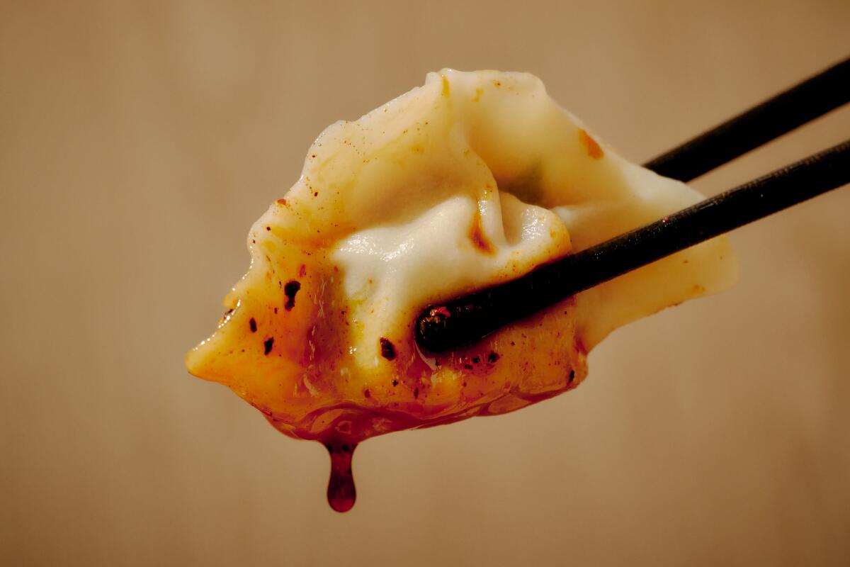 A Pork, Shrimp, Egg and Chive Dumpling held by chopsticks.