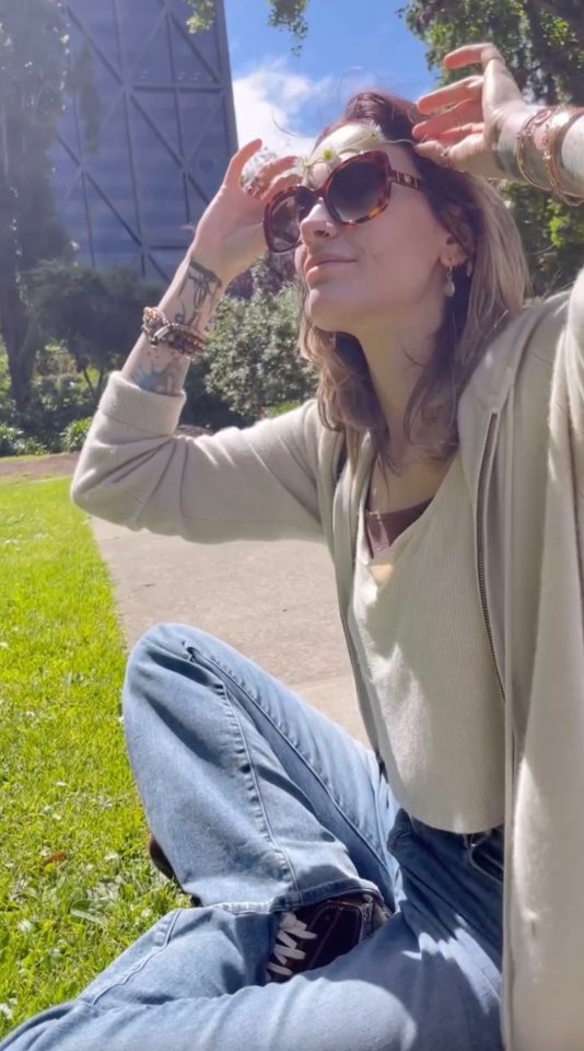 Paris Jackson sitting outside wearing sunglasses and a flower crown.