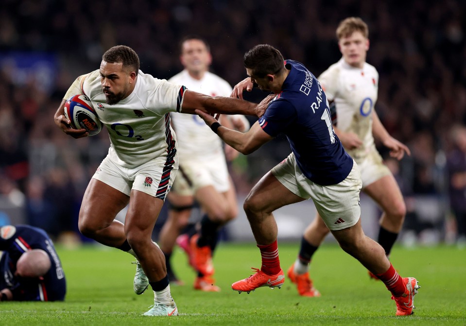 Ollie Lawrence of England scores a try during a rugby match, evading a French player.