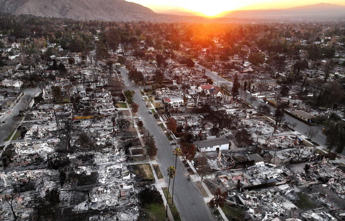 An aerial photo of the sun rising above Altadena homes that burned in the Eaton fire.