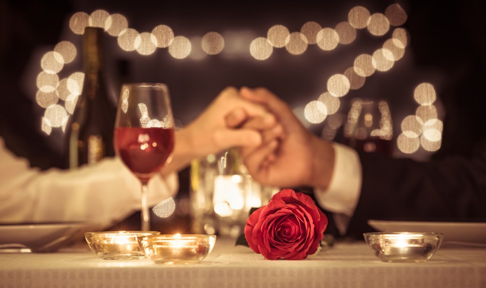 Couple holding hands at a romantic dinner.