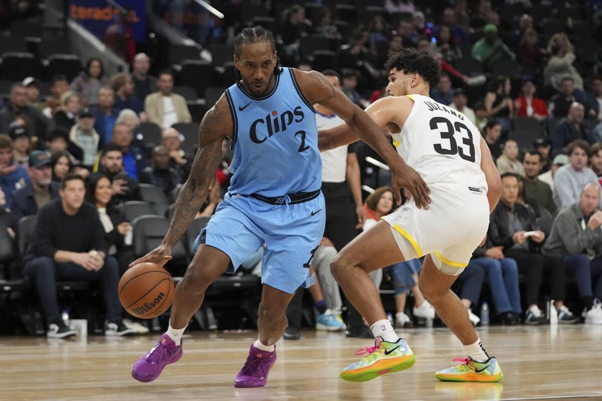 Clippers forward Kawhi Leonard, left, drives past Utah guard Johnny Juzang during the first half Saturday.