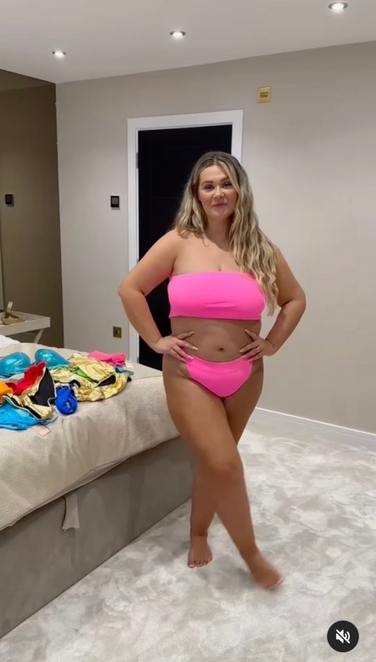 Woman in pink bikini standing in bedroom.