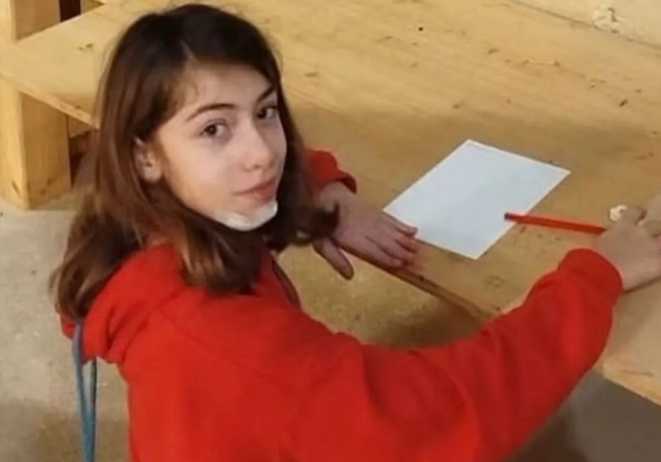 Girl in red sweater working at a desk.