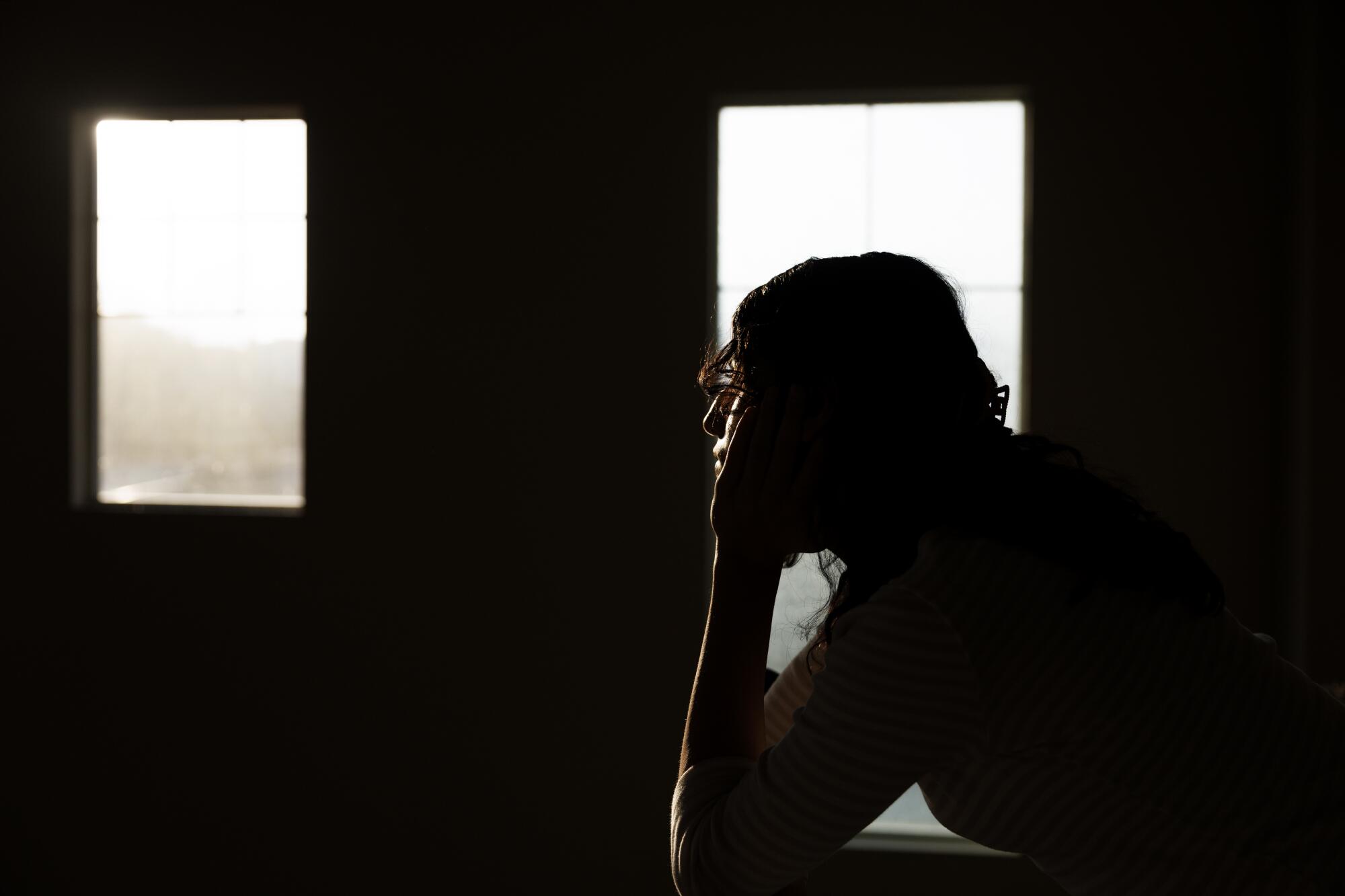 A seated teenager, her chin resting on her hands, looks thoughtfully into the distance. 