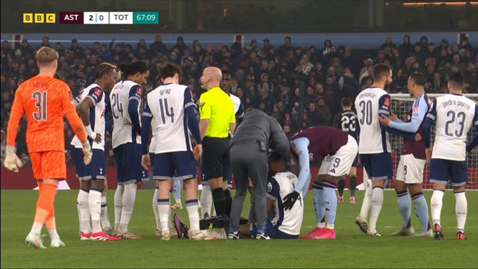 Soccer players attending to an injured player on the field.