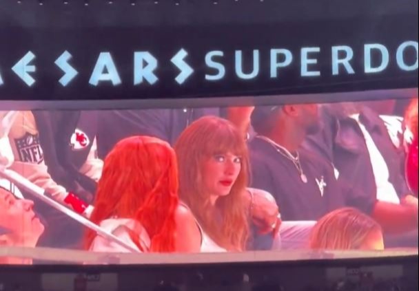 Taylor Swift shown on a jumbotron at a stadium.