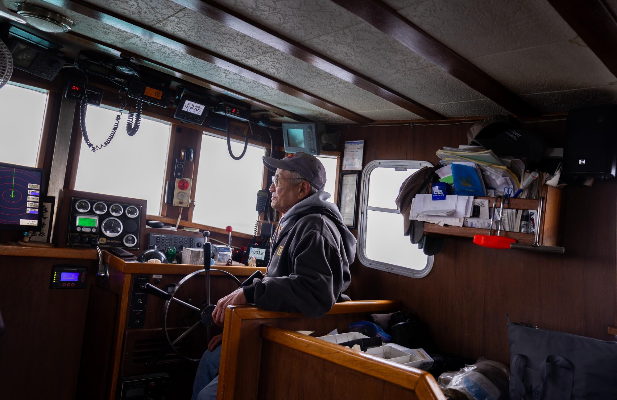 A boat captain scans the waters while navigating among his crab pots. 