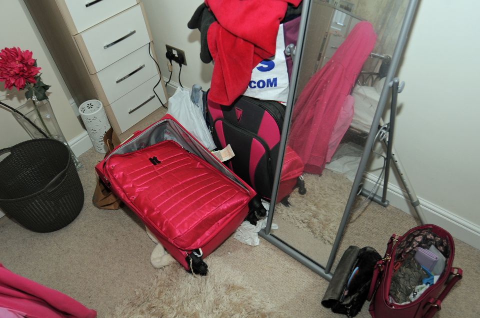 A messy bedroom floor with suitcases, bags, and clothing.