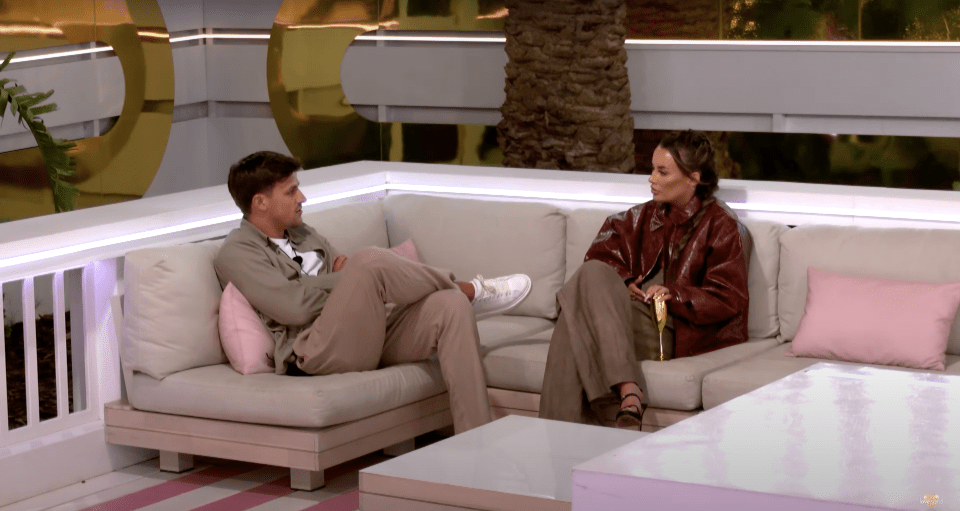 Two people sitting on a couch and talking.