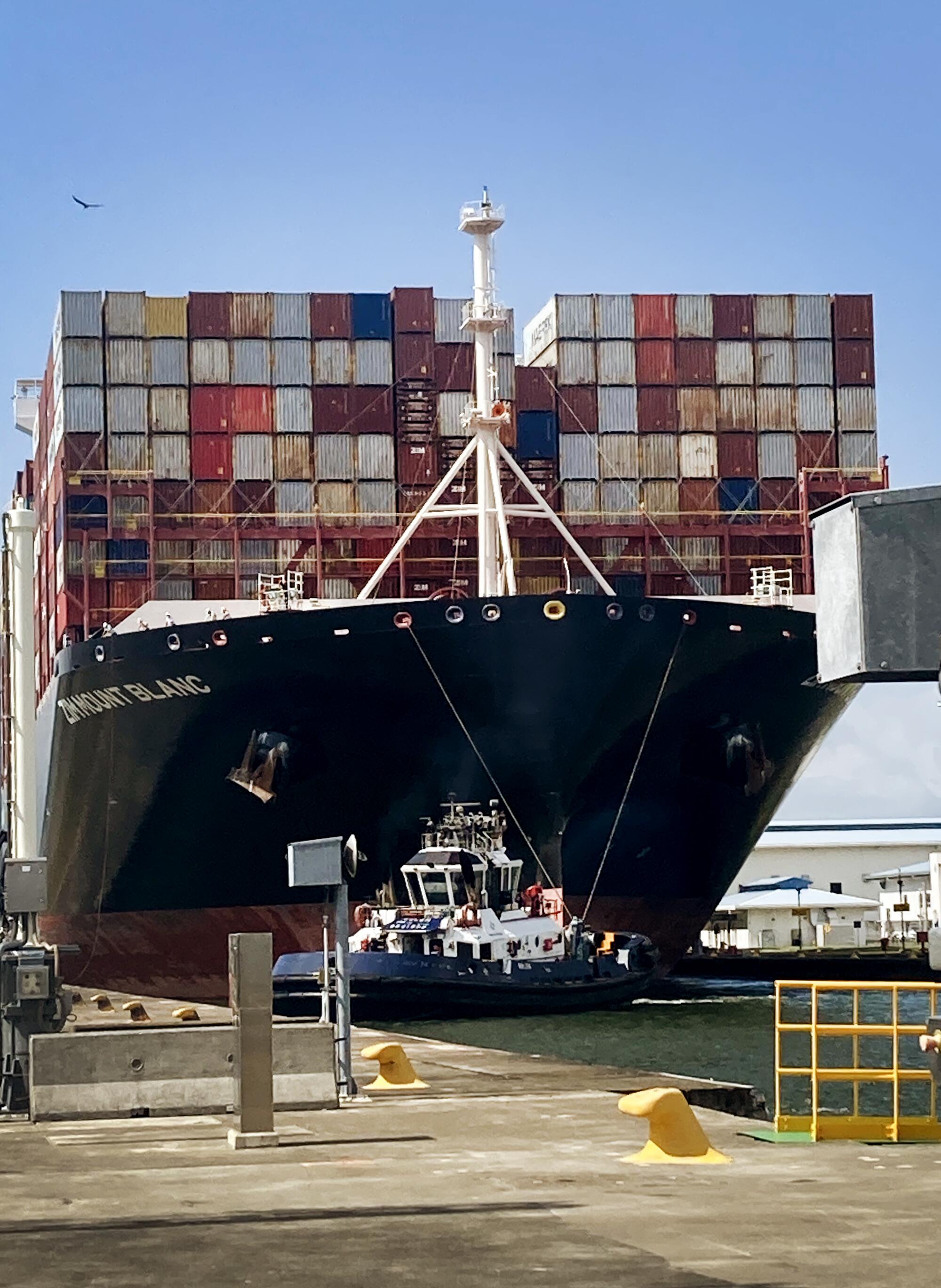 A huge black ship filled with cargo containers 