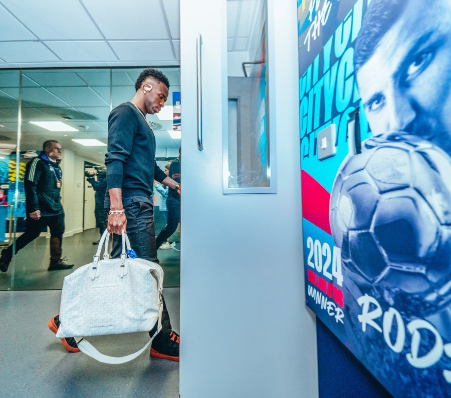 Man carrying a duffel bag walking past a soccer poster.