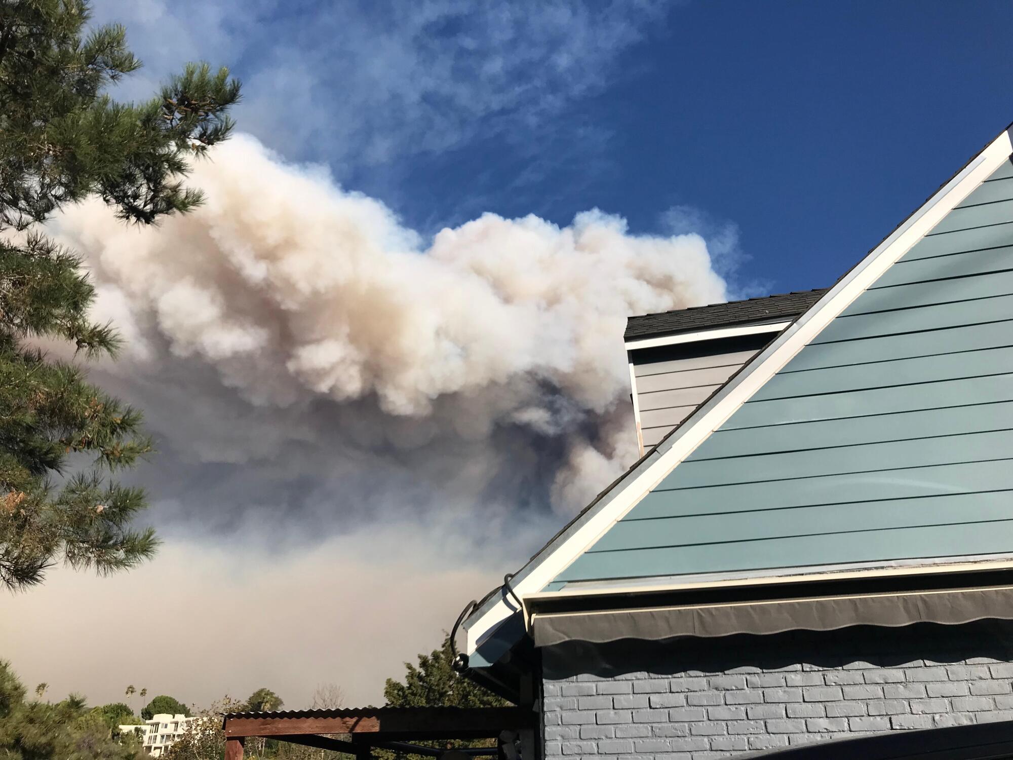 Smoke is seen behind a home that is painted blue.