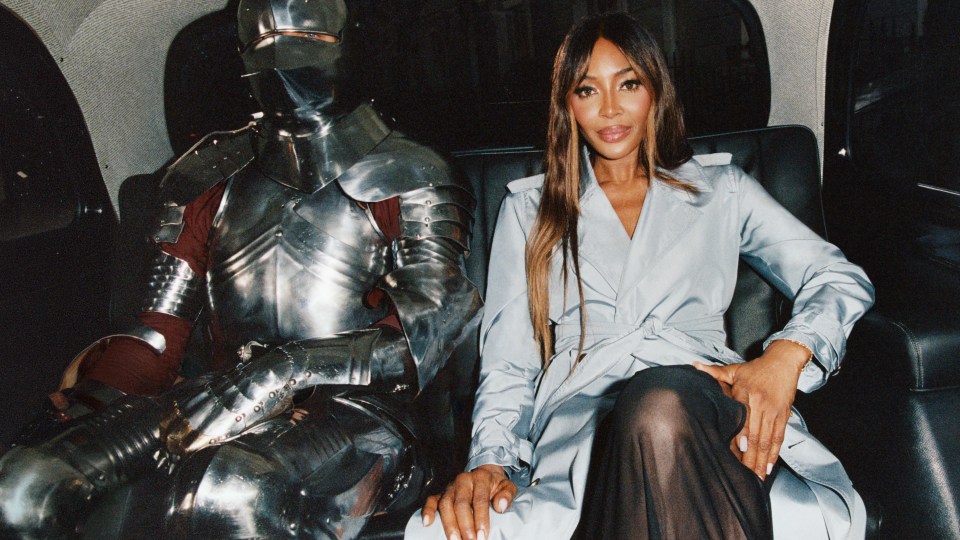 Naomi Campbell and a person in suit of armor sitting in a car.