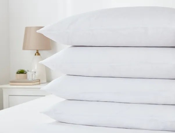 Stack of four white pillows on a bed.