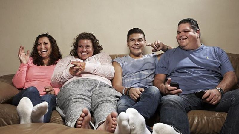 Family sitting on a couch watching TV.