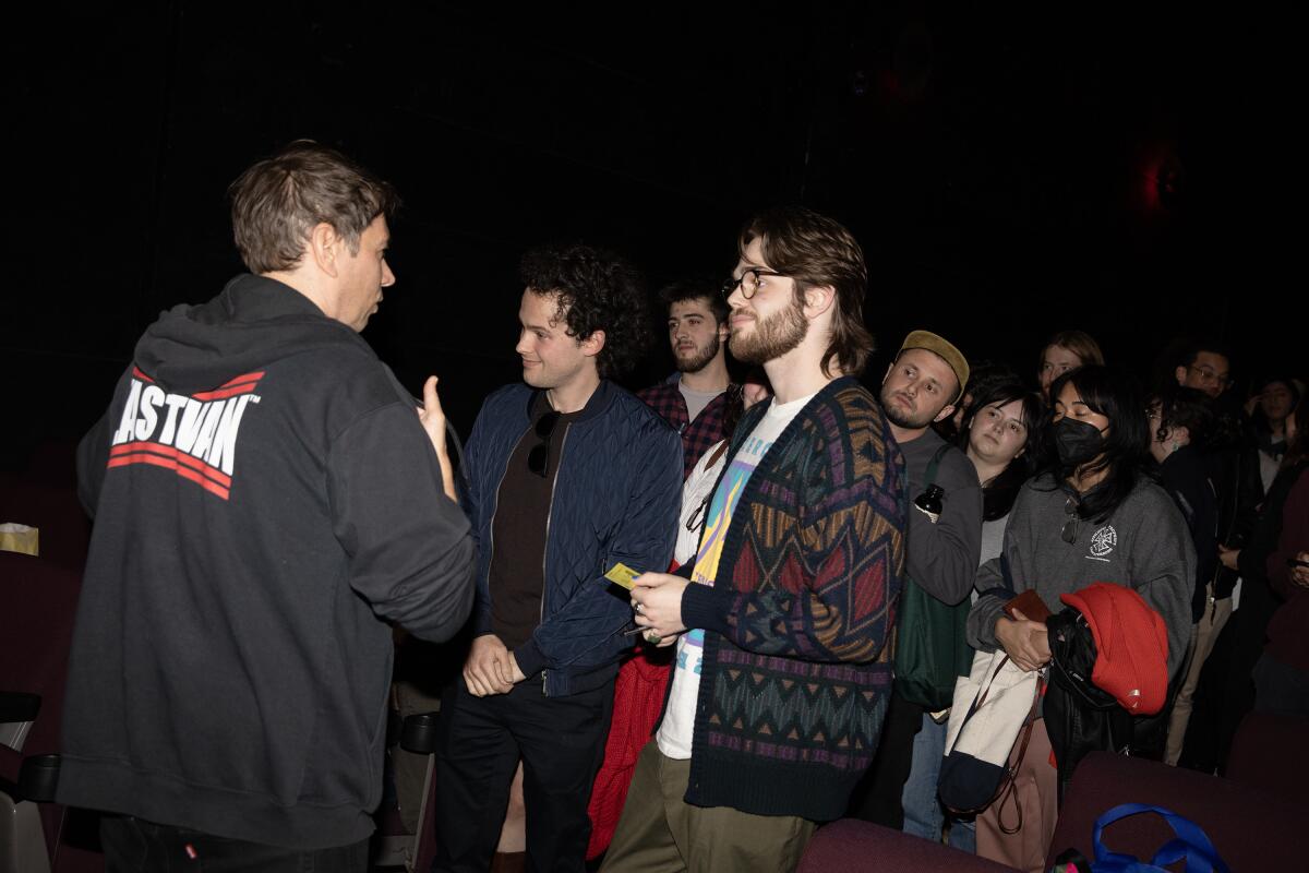 A director speaks with a line of fans at a screening.