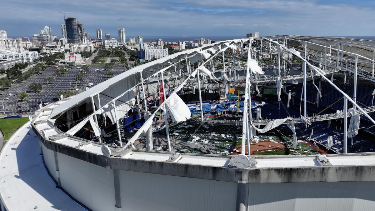 A stadium, its roof ripped off, exposing the interior, against the backdrop of a skyline