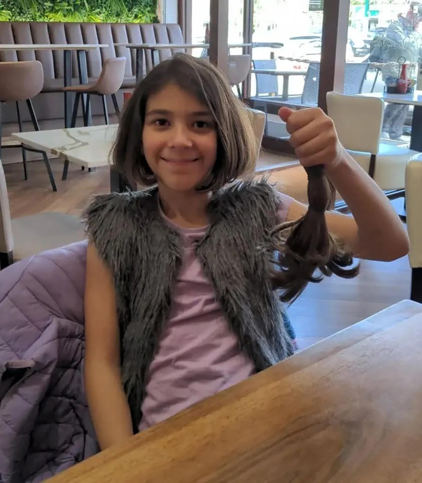 Girl holding up a ponytail of cut hair.