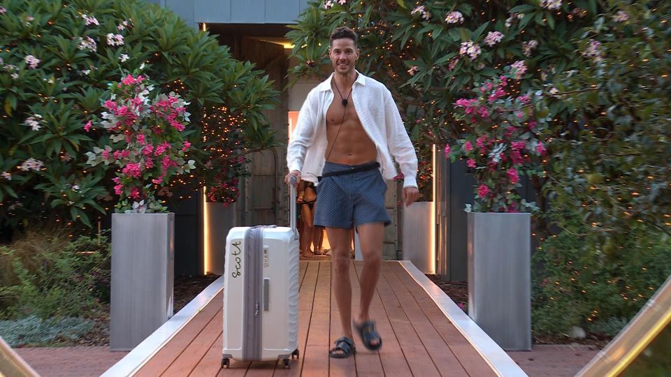 A man arriving at Love Island, pulling a suitcase.